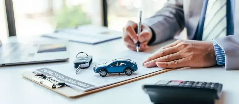 A model car and car keys on an insurance agreement